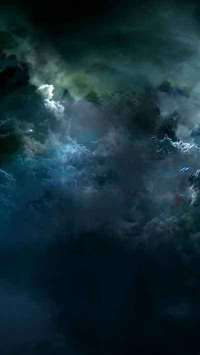 Heavy night clouds pile up in teal and slate, lit from behind so the breaks glow while the lower half sinks into darkness.