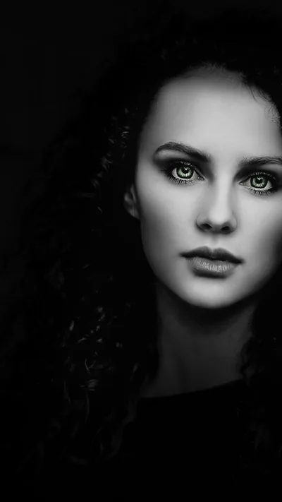 A close monochrome portrait against black, light falling across the eyes and one side of the face.