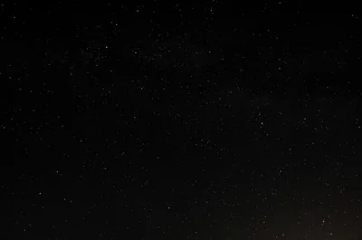 Only a scattering of faint white points across an almost unbroken night sky, with the lower half left darker than the top.