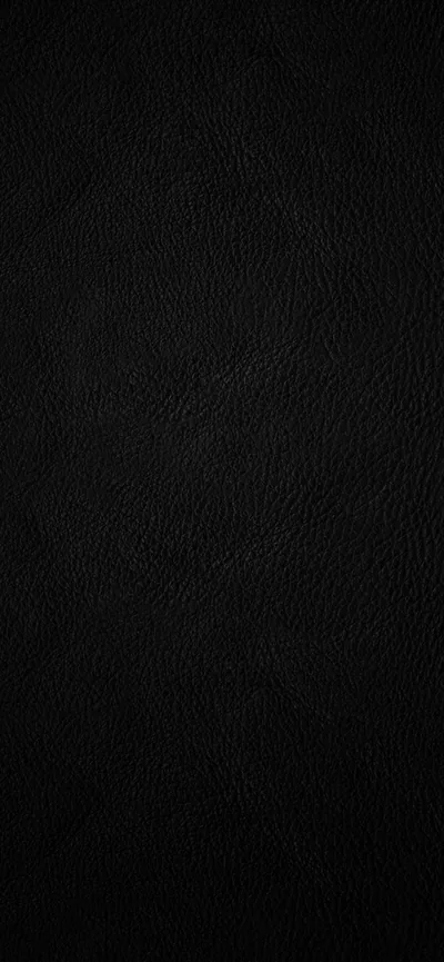 Fine-grain black leather fills the frame edge to edge, the pores catching just enough light down the left side to show the texture.