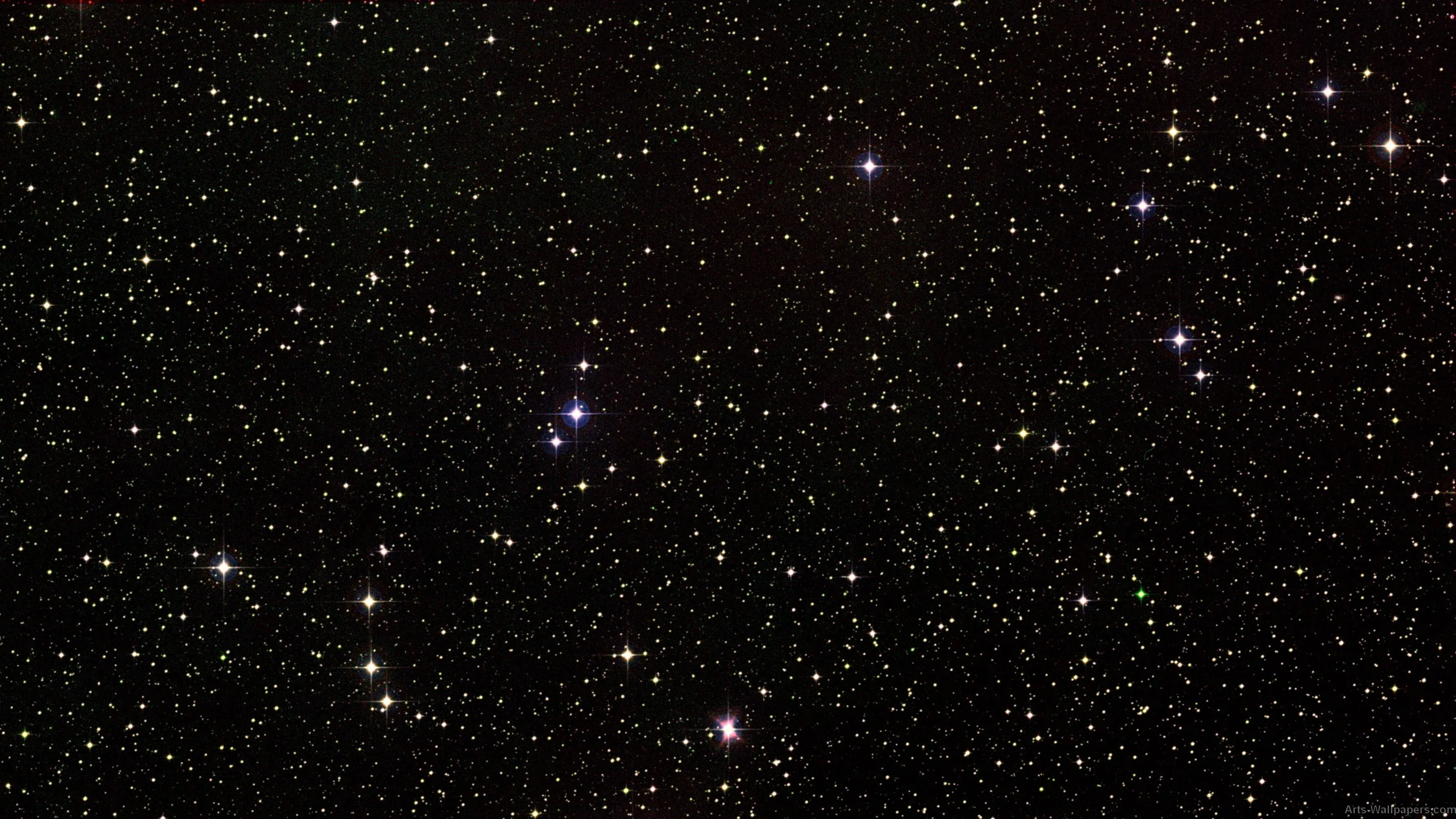 Thousands of stars scattered across black sky, a few burning blue and orange, the rest fading to faint dust.