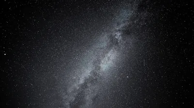 The Milky Way runs corner to corner as a pale grey band of dust and stars, photographed without colour against a deep night sky.