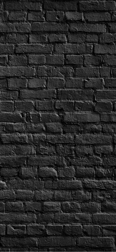 Weathered black brick fills a tall narrow frame, the mortar crumbling in places and the light dropping off toward both side edges.