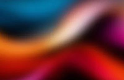Out-of-focus waves of teal, orange, red and magenta roll diagonally across the frame, a pale highlight cutting through the centre like light through frosted glass.