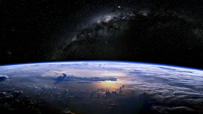 The galaxy's dusty band cuts diagonally through a dense star field while sunset gold picks out the cloud tops along the curve below.