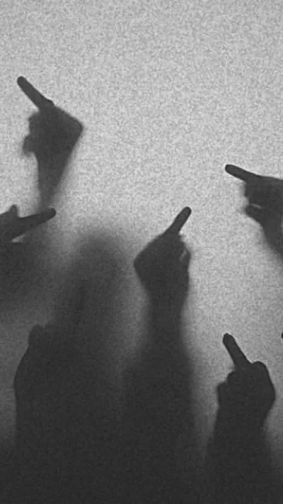 Raised hands press against a sheet of frosted glass, heavy grain flattening everything into grey silhouette.