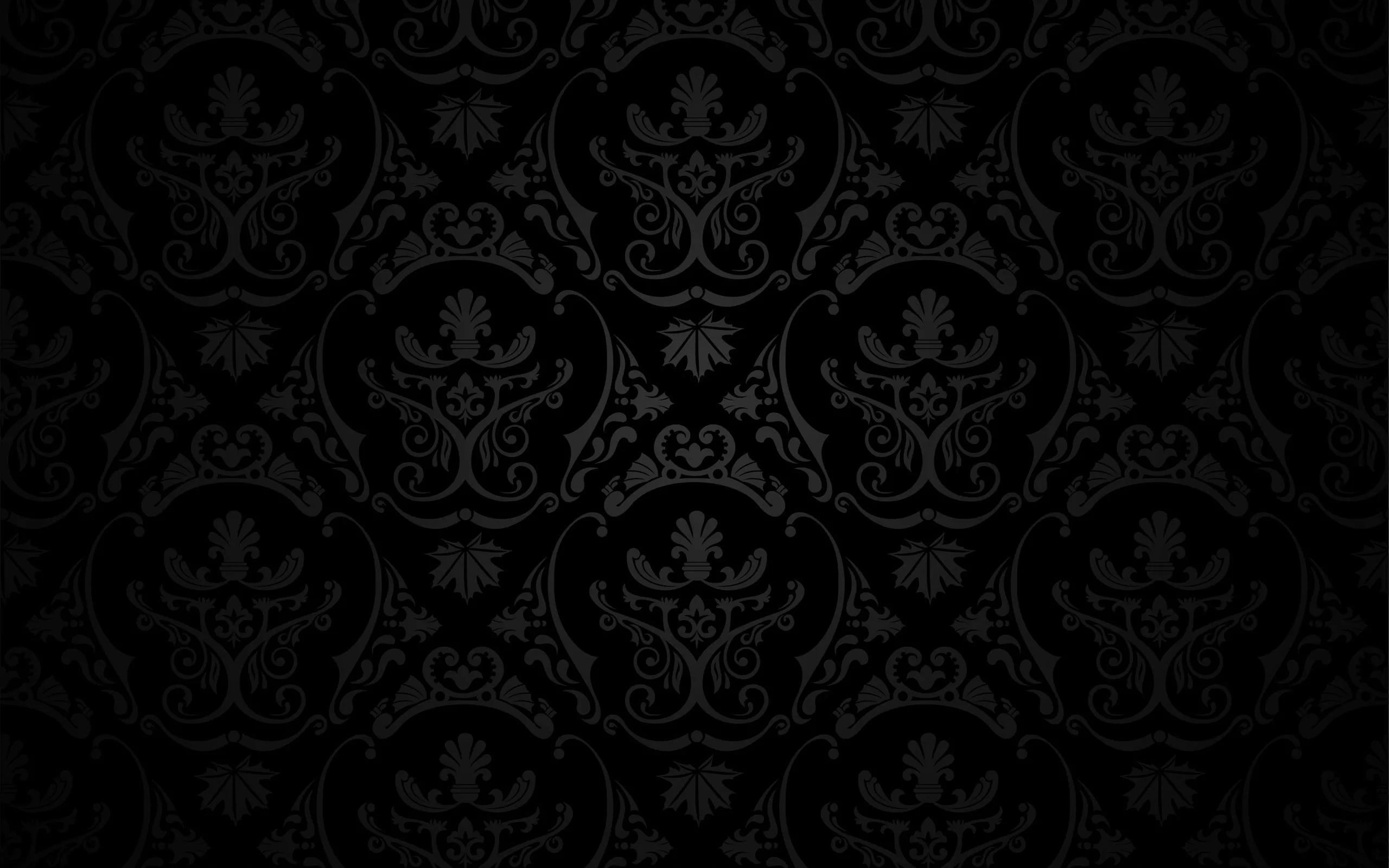 A symmetrical crest and scroll motif repeats in soft grey over black, the light strongest across the middle rows and gone by the edges.