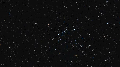A loose cluster of blue and white stars gathers in the centre of the frame, surrounded by fainter red and gold points on black.