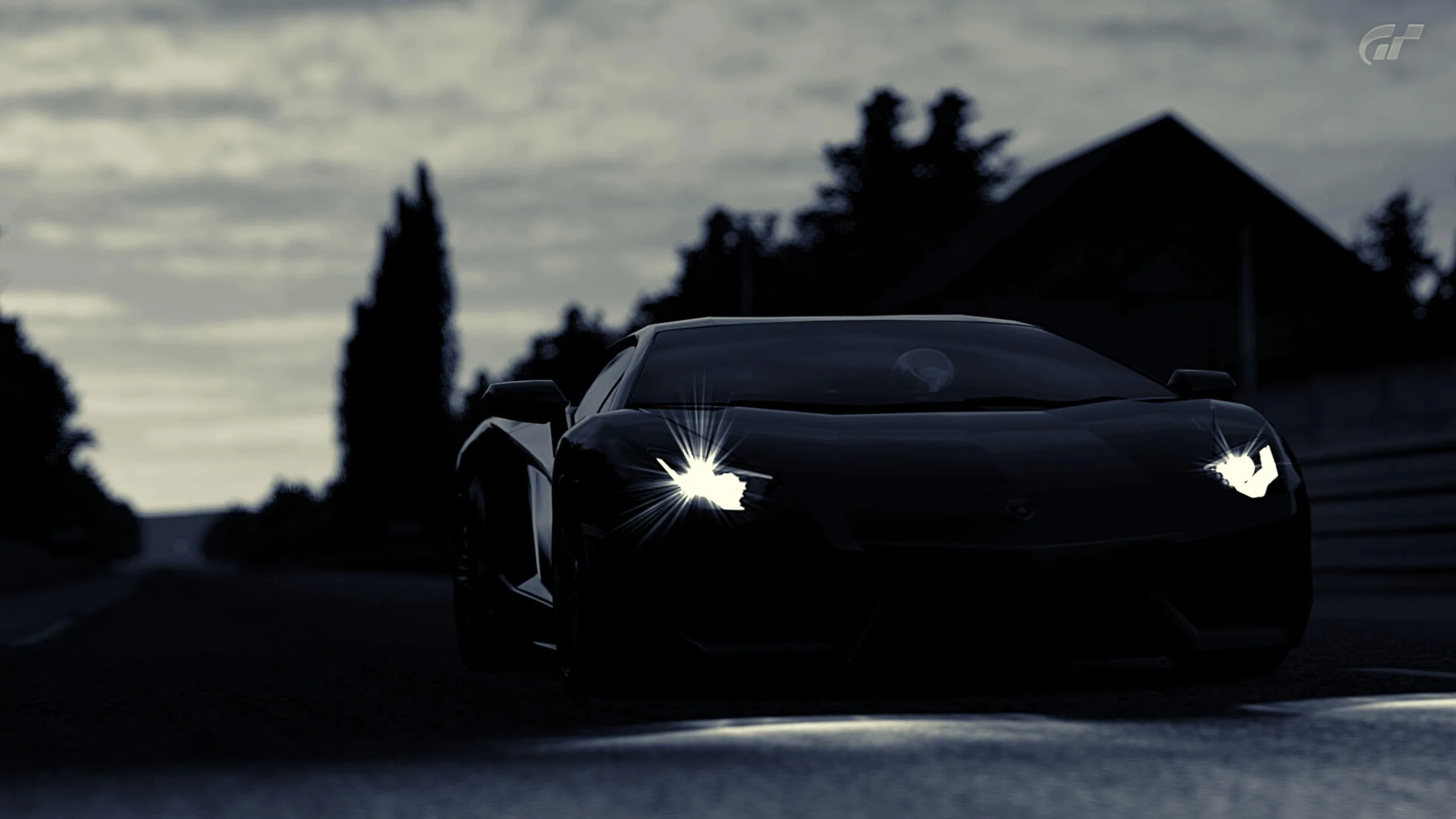 Almost the whole frame is dark blue — only the headlights, a strip of guardrail and the edge of a barn roof separate the car from the evening sky.