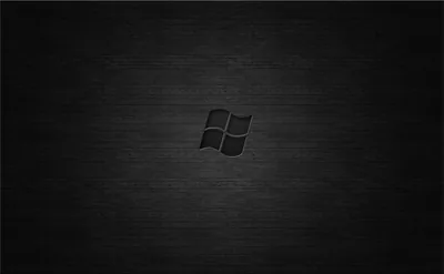 The four-pane Windows mark sits small at the centre of a brushed dark metal panel with a soft glow behind it.