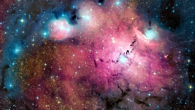 Rose-coloured gas fills most of the frame, cut by black dust lanes, with tight groups of blue-white stars burning at the top corners.