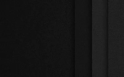 Layered fabric panels run side by side in charcoal and black, the seams between them catching just enough light to separate each layer.