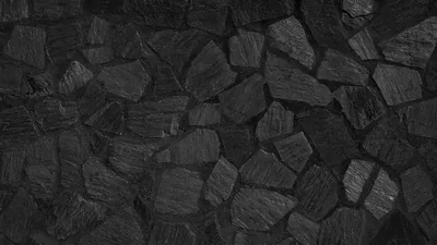 Irregular slabs of split slate are packed together with dark mortar between them, side lighting picking out the rough chipped faces.