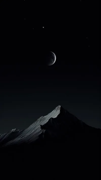 A thin crescent sits high over a single lit mountain ridge, the slopes below and the sky around it dropping into black.