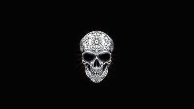 A small skull made of fine white filigree floats at the centre of a wide black frame, its swirls dense at the crown and open at the jaw.