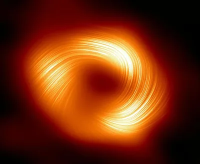 Bright orange filaments spiral around a dark centre in a telescope-style image, the glow falling off quickly into surrounding black.