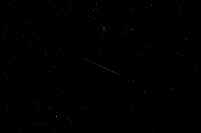 A short meteor trail crosses the middle of an otherwise quiet sky, the stars thin and the corners almost pure black.