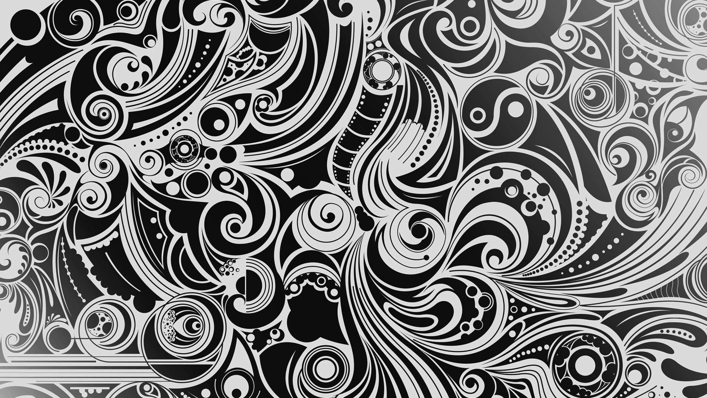 Curling paisley and spiral motifs fill the whole frame in fine white line work over black, with no quiet space left.