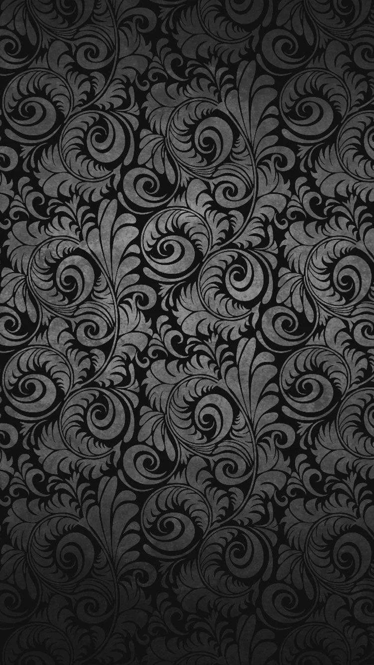 A dense damask of curling leaves and scrolls repeats edge to edge in charcoal on black — closer to texture than picture at arm's length.