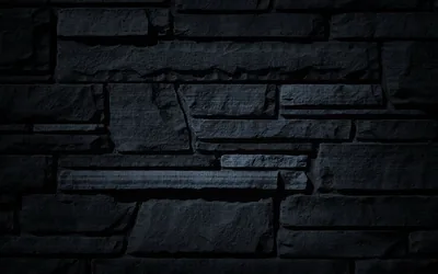 Irregular stone slabs stacked in uneven courses, lit softly from the upper left with the corners dropped into shadow.