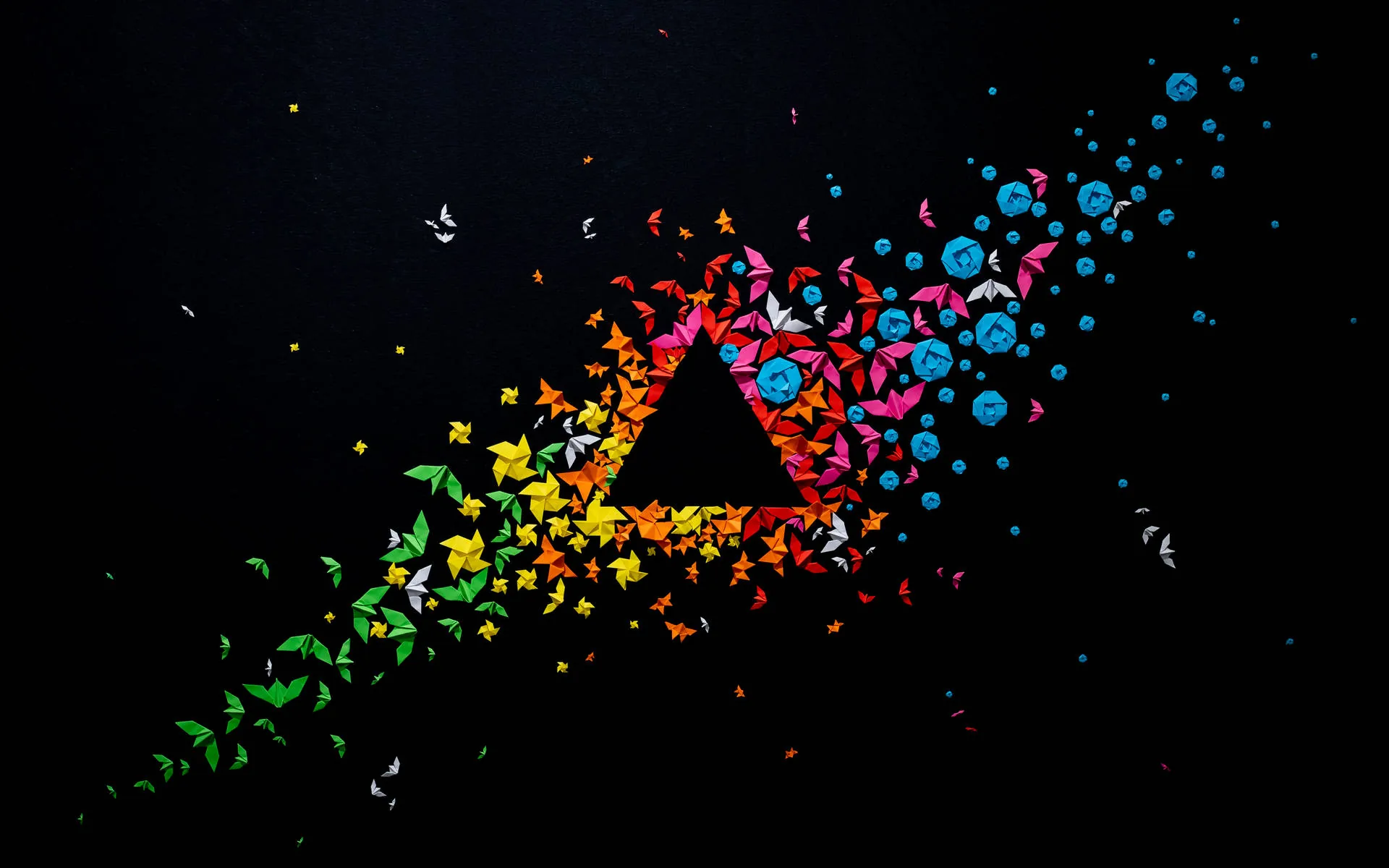 A triangle outline made of butterflies and small circles sits at the centre, the swarm scattering diagonally toward the upper right in yellow, red and blue.