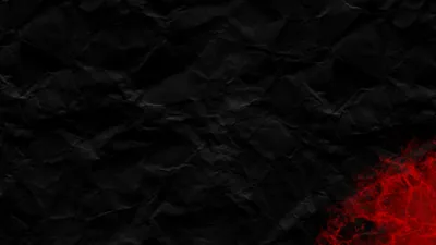 Creased dark paper fills the frame with red light burning up from the bottom right corner.