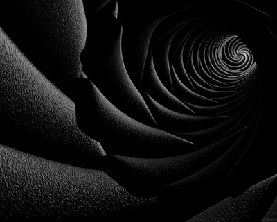 Grainy black petals coil into a spiral that tightens toward a lit point in the upper right, shadows deepening steadily down the left side.