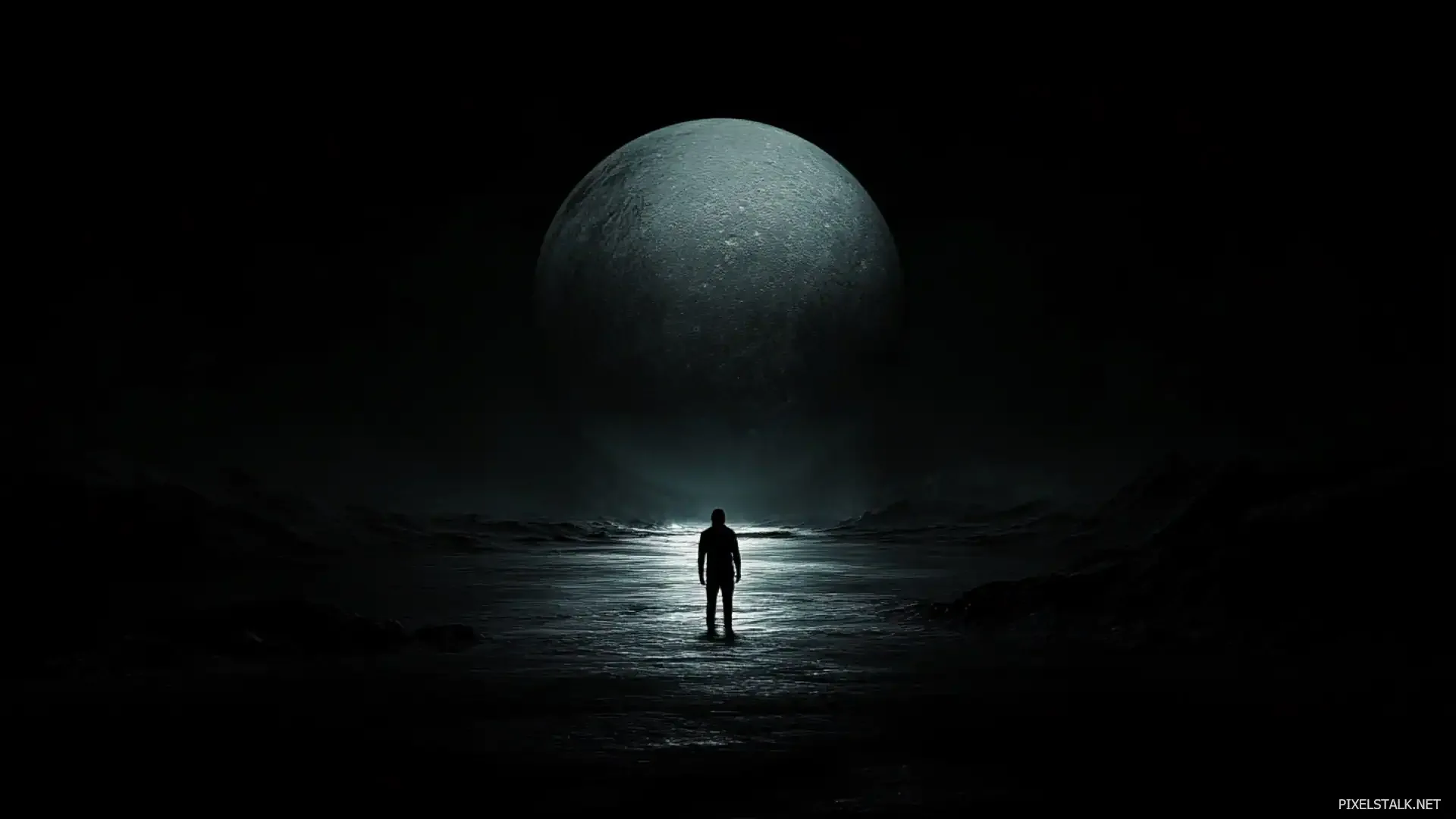 A lone silhouette stands on wet ground while an enormous moon fills the sky behind him.
