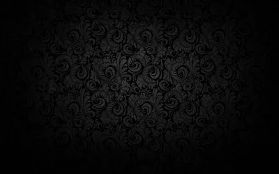 A repeating floral scroll printed in charcoal on black, lit softly through the middle and sinking into a heavy vignette at every corner.