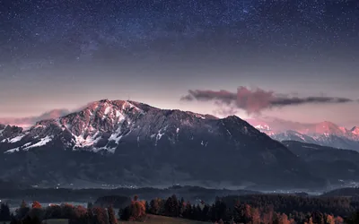 Stars fill a violet sky above a Bavarian massif still touched by pink dusk light, thin fog and dark autumn woods keeping the valley floor quiet.