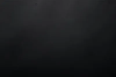 A featureless dark wall with a low haze of grey spreading across the middle and right, one small speck of dust near the top left corner.