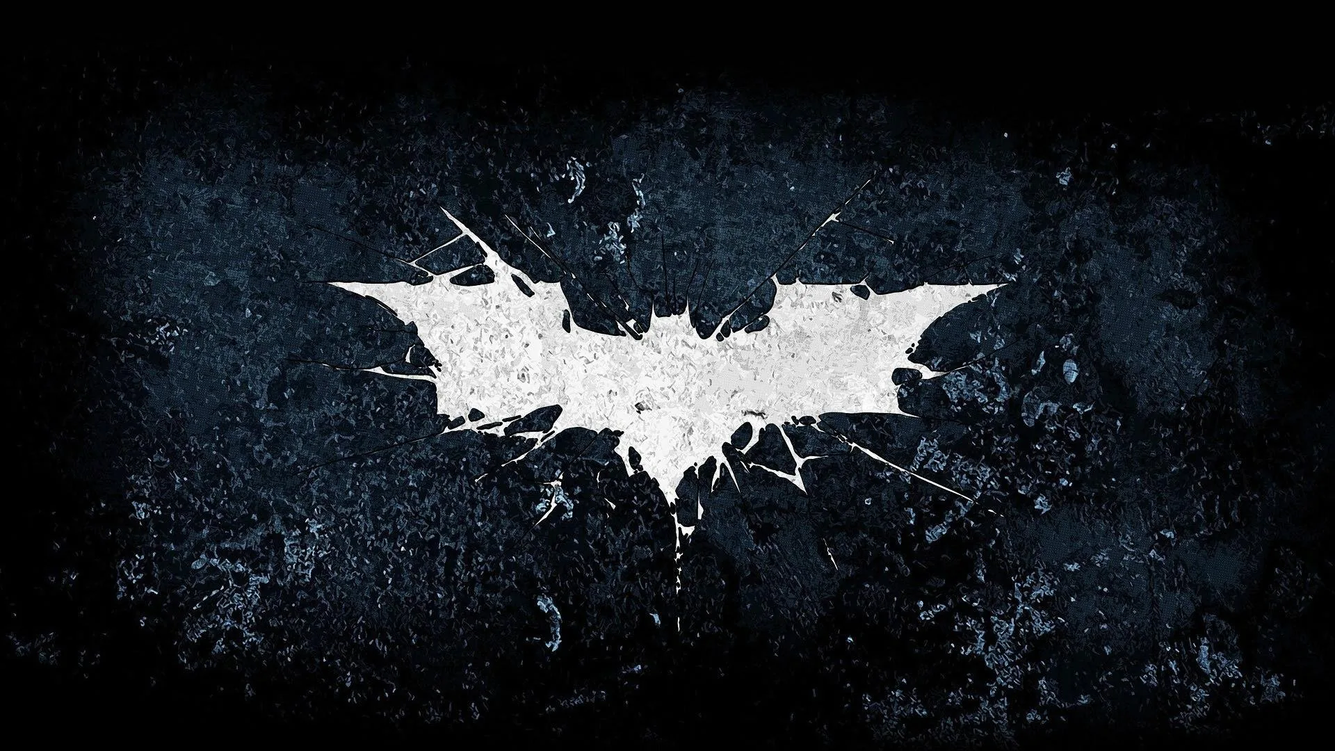 The bat symbol sits cracked and chipped in white across a scratched dark wall, the corners falling away into black.