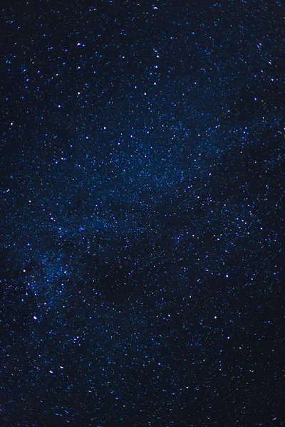 Thousands of fine star grains dust a dark navy sky, a faint galactic band crossing the middle, most of the frame dark enough for battery saving.