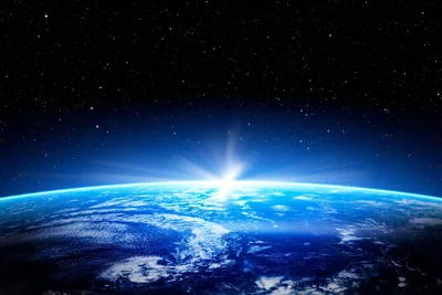 A white star flare bursts on the rim dead centre, deep blue cloud decks rolling below, and the top half stays dark for menu bars and clocks.