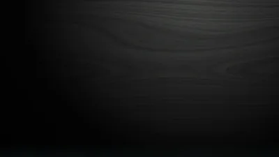 Faint horizontal grain runs across a stained dark board, brightest through the upper middle and falling away to black at every edge.