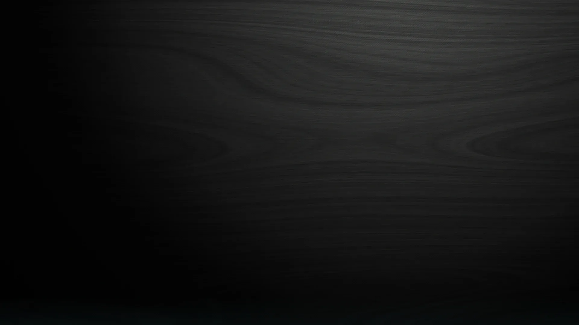Wide wood grain runs horizontally across a near-black plank surface, the faint lines showing along the top before the base fades out.