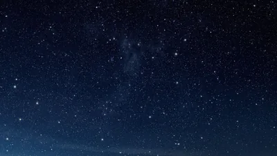 An even sprinkle of small stars over deep blue with faint cloud haze through the middle — calm enough for desktop icons and text.