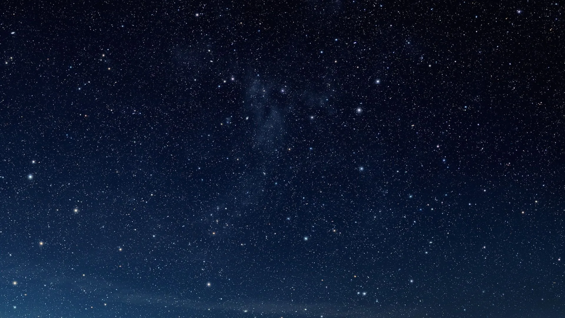 An even sprinkle of small stars over deep blue with faint cloud haze through the middle — calm enough for desktop icons and text.