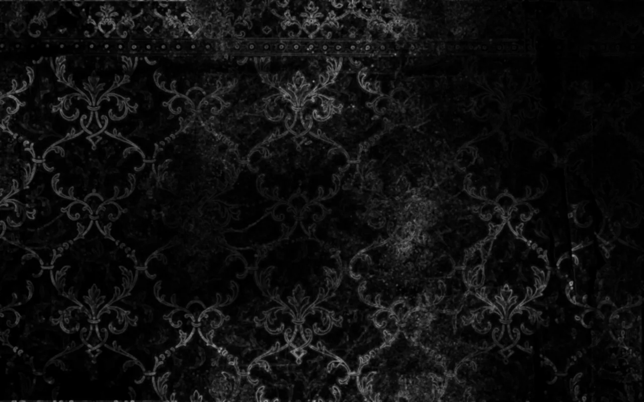 A worn damask pattern shows through grime and scratches on a black wall, heaviest around the middle and lost entirely in the corners.