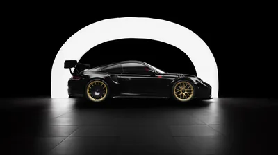 A black Porsche race car in dead side profile, gold centre-lock wheels and a tall rear wing outlined by a glowing white arch on an otherwise black wall.