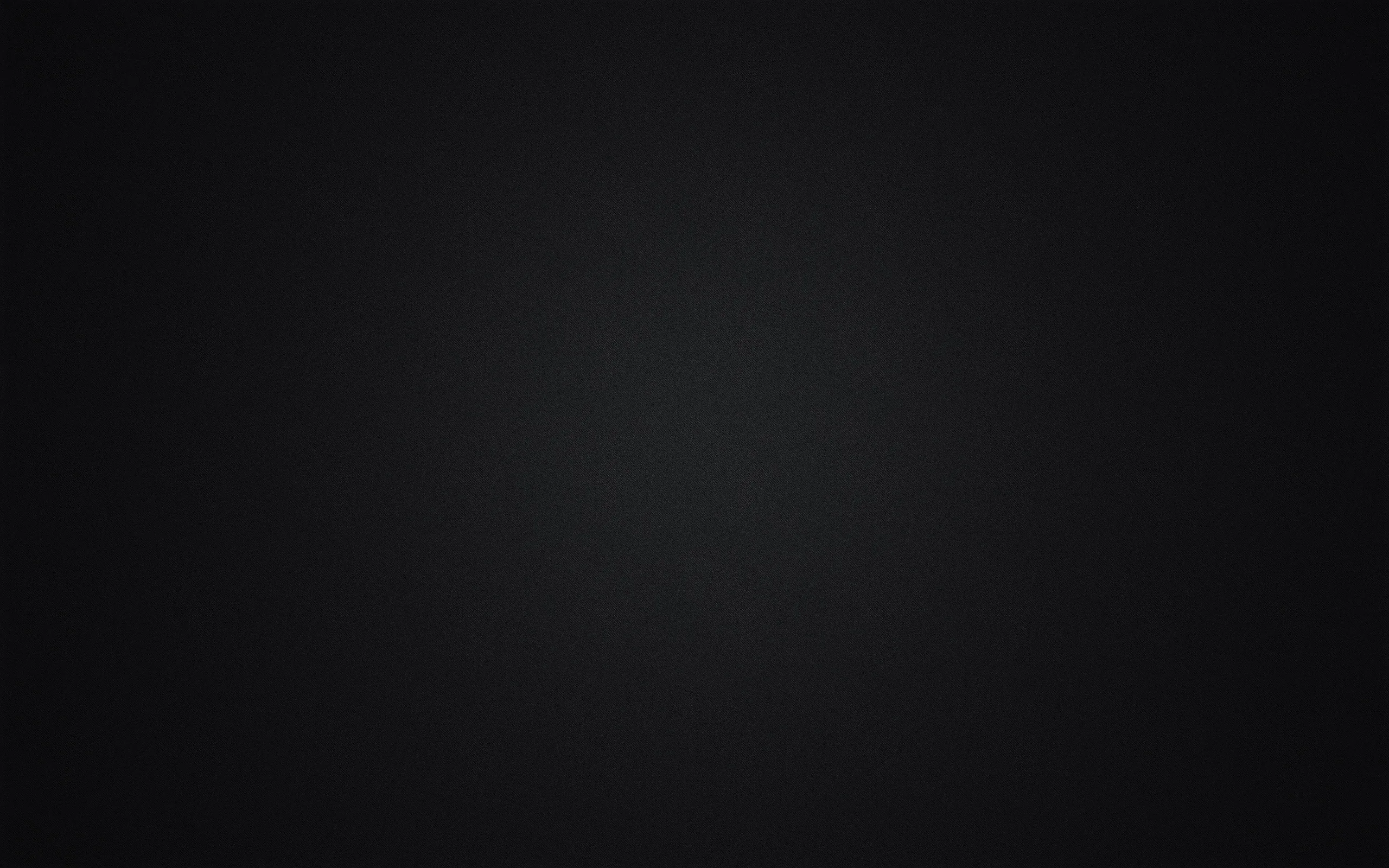 A studio-style backdrop where a round patch of grey light sits just above centre, falling away evenly into black corners with no texture in sight.