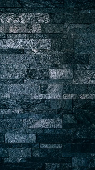 Narrow stone strips run in tight horizontal rows up a tall frame, the blue-grey faces rough enough to catch light along every ridge.