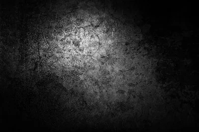 A worn concrete surface takes a soft pool of light near the top left, the rest of the wall falling into shadow.