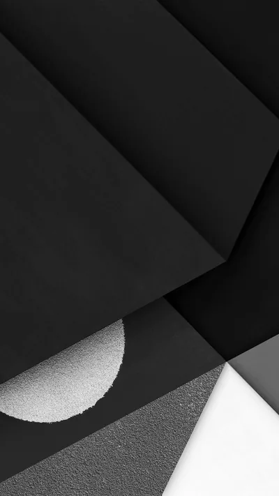 Angled sheets of matte black, concrete grey and white overlap like cut paper, with a single glittering half-circle set into the lower left.