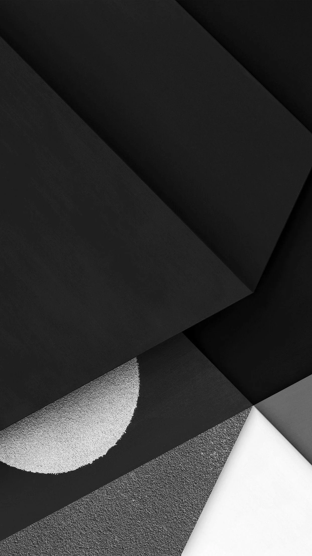 Angled sheets of matte black, concrete grey and white overlap like cut paper, with a single glittering half-circle set into the lower left.
