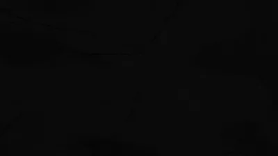 Almost the entire frame sits at black, with barely-there smudges of charcoal drifting through the lower left and upper middle.