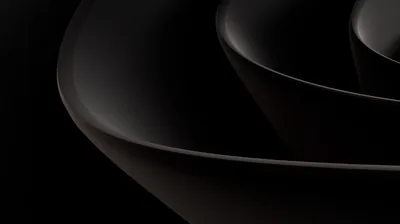 Two nested dark bowls curve across the frame, a warm brown tone in the surface where light rakes across it.