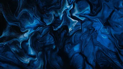 A paint pour in deep blue where pale wisps curl through the left and centre, both lower corners falling to black, usable as a subtle desktop backdrop.