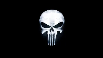 The wide skull emblem with elongated teeth glows white at the centre of a black frame, edges softened to a faint haze.