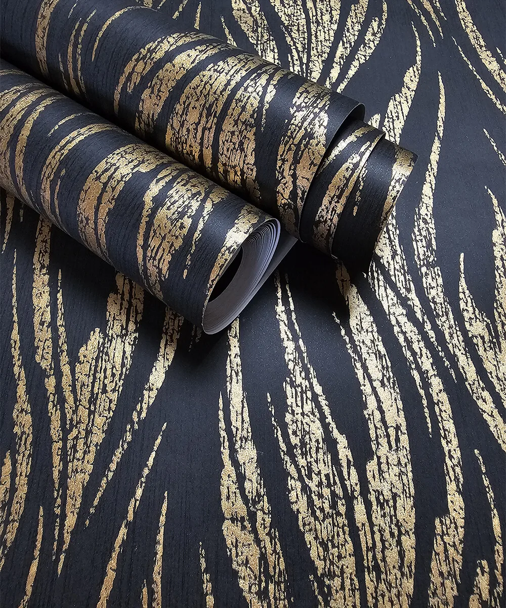 Two part-unrolled rolls lie across a black sheet printed with feathery gold brushstrokes that sweep upward in loose vertical clusters.